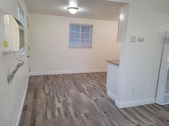 View of kitchen eating area from living room. Window AC unit and door to backyard on left.