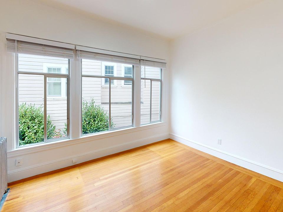 Sunlit room with a large window and wood-like flooring