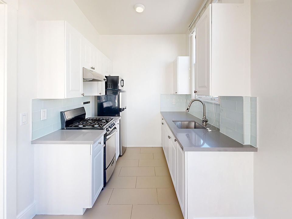 Kitchen with multiple cabinets, refrigerator, stove, range hood, and sink