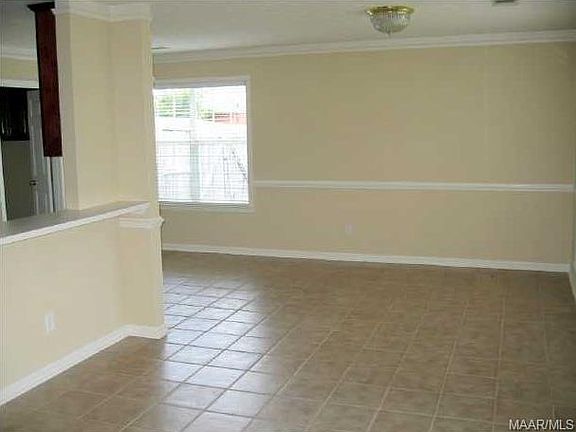 From the fireplace in the Greatroom, this view is of the dining room with wide windows not shown on the right, with the breakfast area in front of the windows shown, the pass thru window into the kitchen, and the doorway shown going into the laundry room