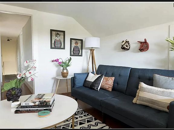 View of the airy living room, which features hardwood floors, elegant arches in the ceiling, and two storage closets.
