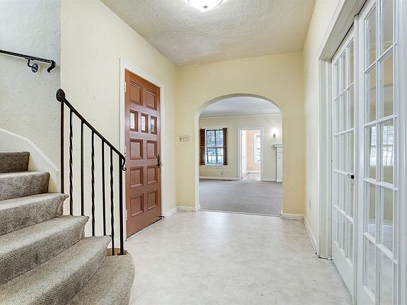 Gracious foyers has circular staircase, archway and French doors