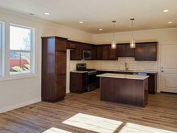 Kitchen with dark cabinets, window lighting and entrance to main area.