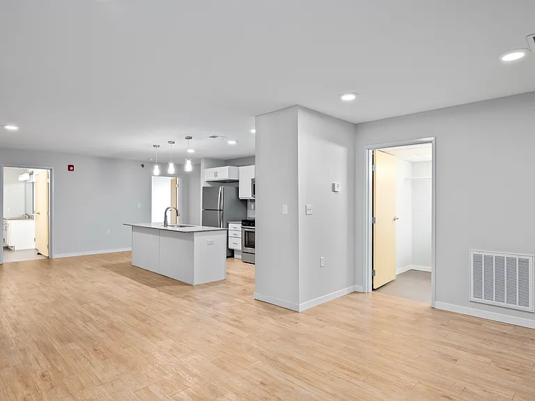 Modern open-concept apartment interior with sleek kitchen island, light wood flooring, and spacious rooms. Modern open-concept apartment interior with sleek kitchen island, light wood flooring, and spacious rooms.