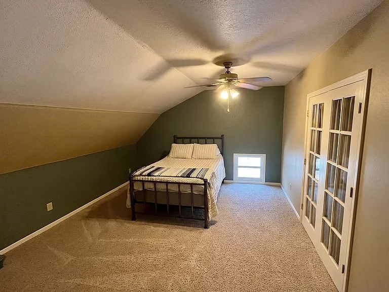 Upper-level bedroom with a comfy full bed and glass French doors that open to an adjoining room for added light and space.