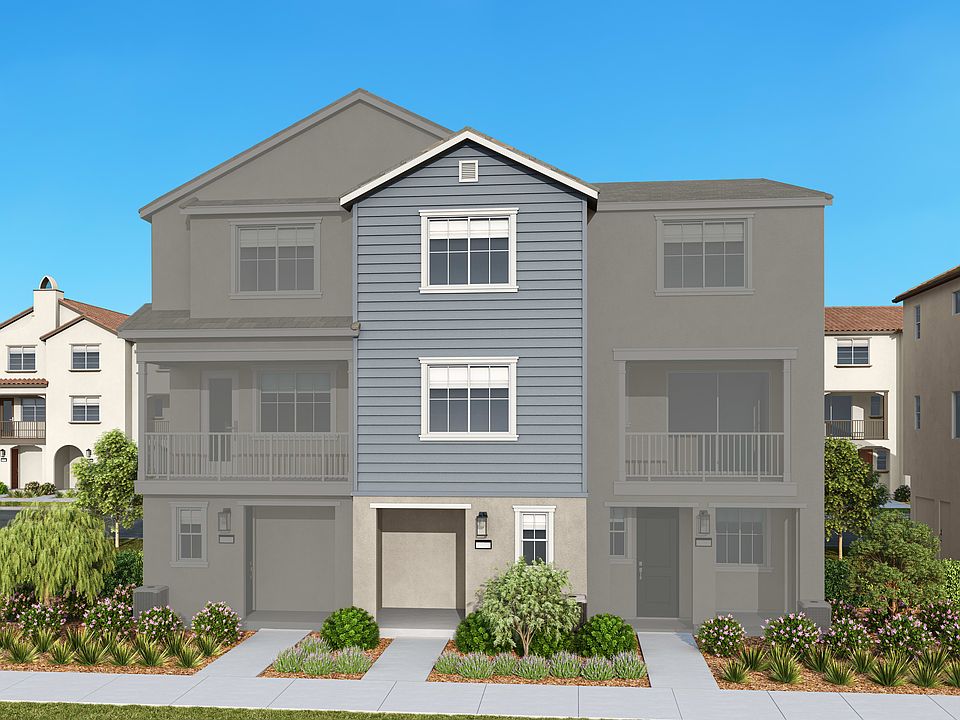 A multi-story residential building with a gray exterior, surrounded by landscaping and set against a