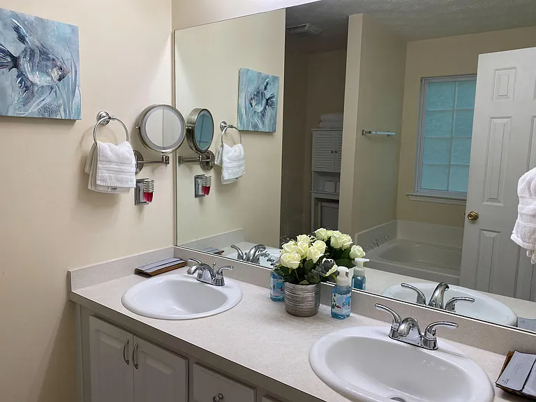 Shared bath with a double-sink vanity, ample counter space, and a tub/shower combo plus built-in storage cabinet.