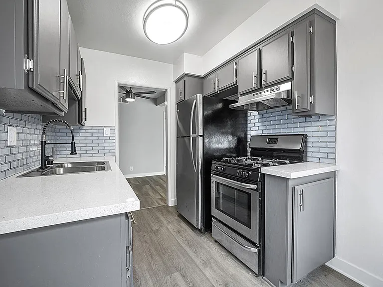 Tiled kitchen with stainless steel oven, fridge, and fixtures.