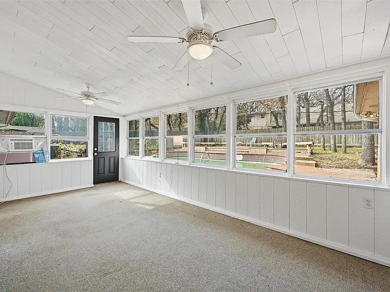 Enclosed sunroom with wall-to-wall windows, ceiling fans, and direct access to the backyardideal for lounging or a home offi
