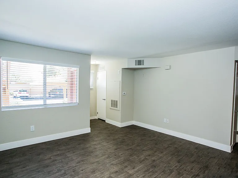 Living area with wood-style flooring, large baseboards, two-tone paint, and window.