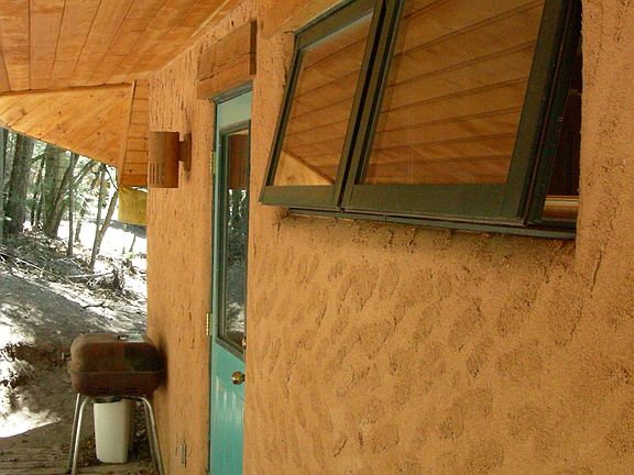 Back porch with private entry, clothesline, firewood storage, and outdoor rope lighting.