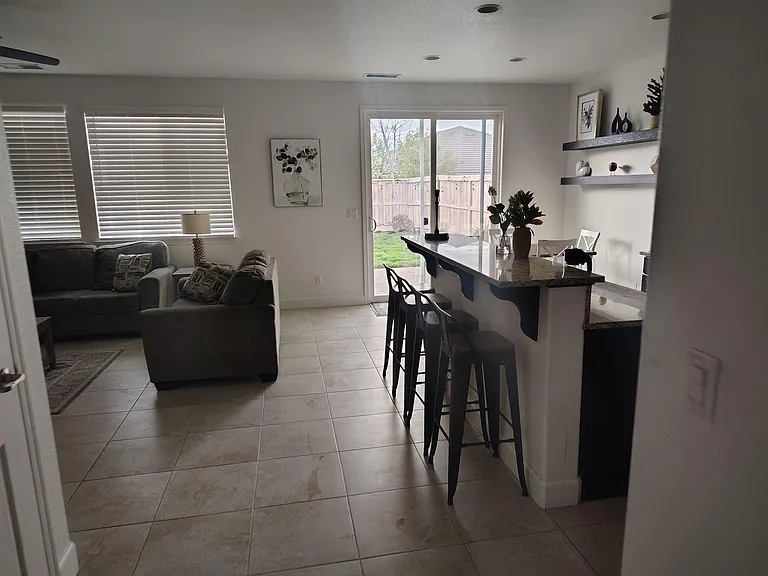 Open-concept living area with a breakfast bar, seating, and a sliding glass door providing easy backyard access.
