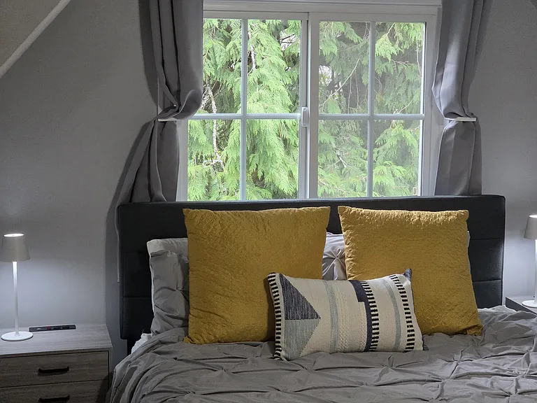 The inviting second bedroom is a peaceful escape with a queen bed and custom nightstands. Thoughtful darkening shades offer comfort and privacy.
