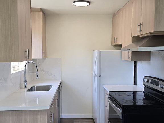 Newly furnished kitchen with new wooden cabinets, marble countertops, and hardwood flooring. Also includes a stove/oven, dishwasher, and refrigerator/freezer.
