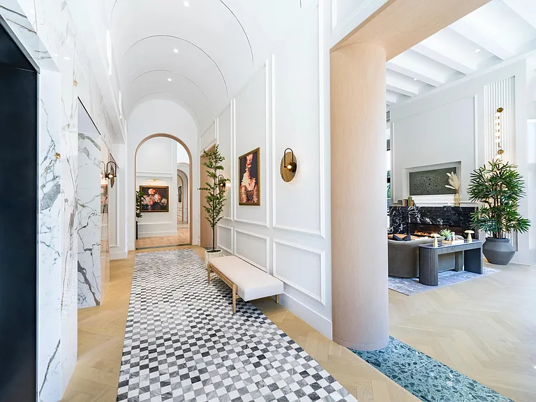 Light-filled community corridor with arched passages, curated artwork, and refined finishes creating an inviting transition between shared living spaces.