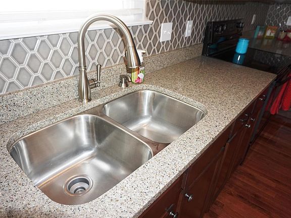 Deep double sinks with gooseneck faucet; quartz countertops, and awesome backsplash!