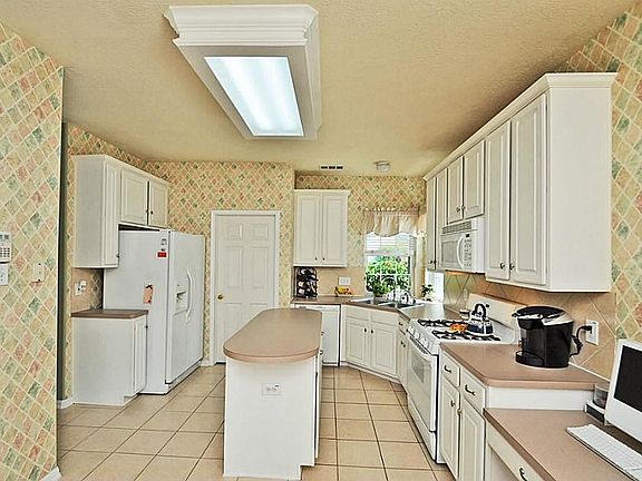 ...Island KITCHEN with many cabinets, chef's desk, large utility room and tile floors.