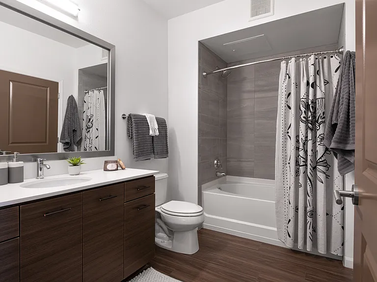 Apartment bathroom with large soaking tub and wood-style flooring.