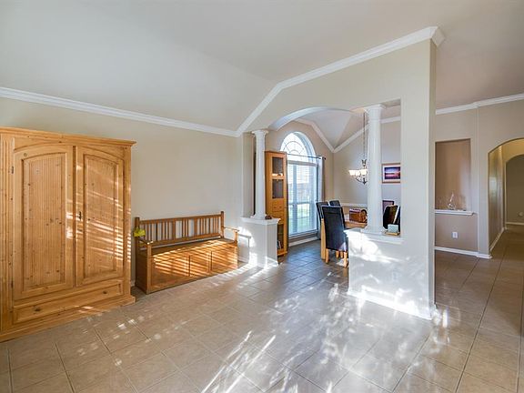 Formal den with beautiful columns and crown molding open to dining room.