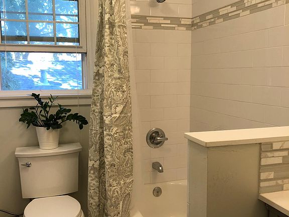 Beautifully remodeled upstairs full bath with tub/shower combination, white subway tile surround, grey maple cabinetry, tile/glass/marble accents, restoration hardware lighting....