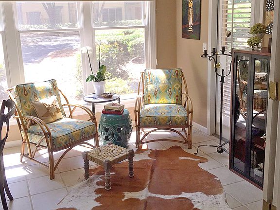 Bright sun room with side entrance, large storm windows, tile flooring, ceiling fan, French doors.