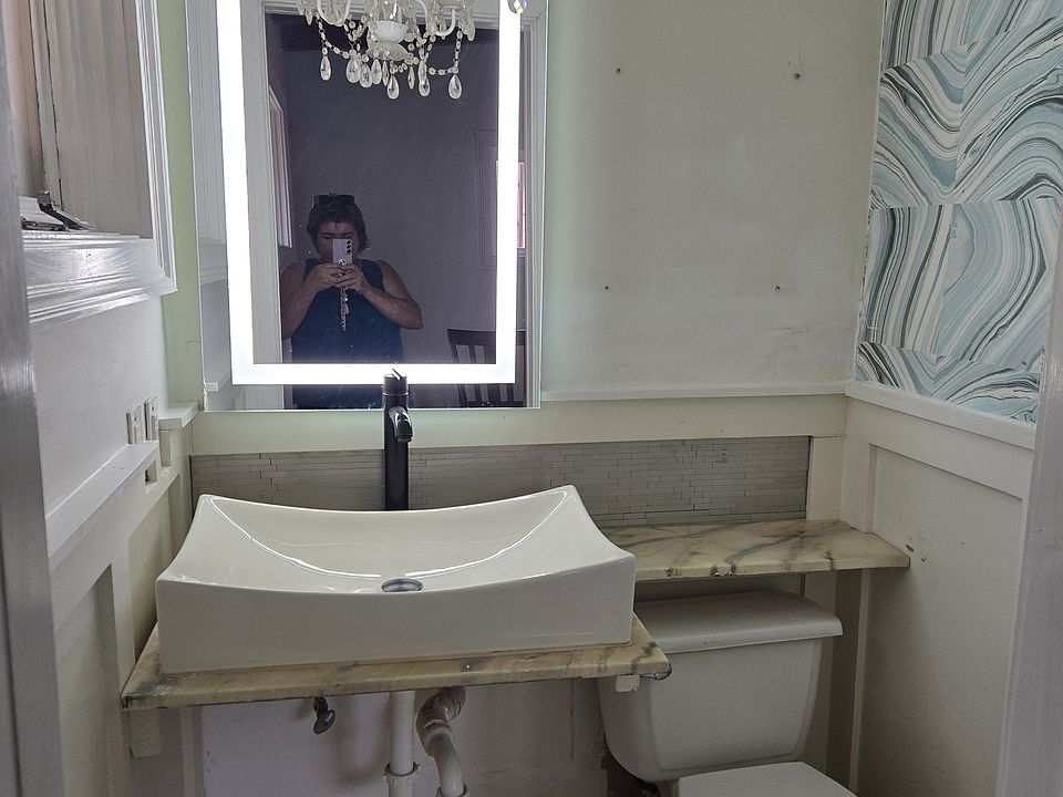 Customized half bath, makeup lights built into the mirror. Large sink and beautiful chandelier. Marble floor