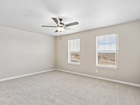 The master bedroom is spacious with large windows and a ceiling fan.