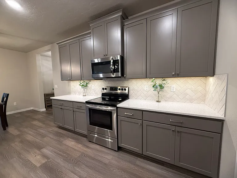 Gray shaker cabinets, quartz counters, and herringbone tile backsplash. 
Electric range (gas line available for conversion.)
