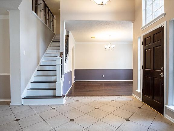 Inside the entry you find elegant tile floors and a view of the wooden staircase with wrought iron spindles.