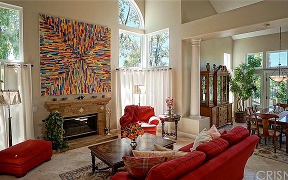 Formal Living Room with soaring ceilings, triple stacked windows, fireplace, travertine tile floors and formal dining with french doors to back yard