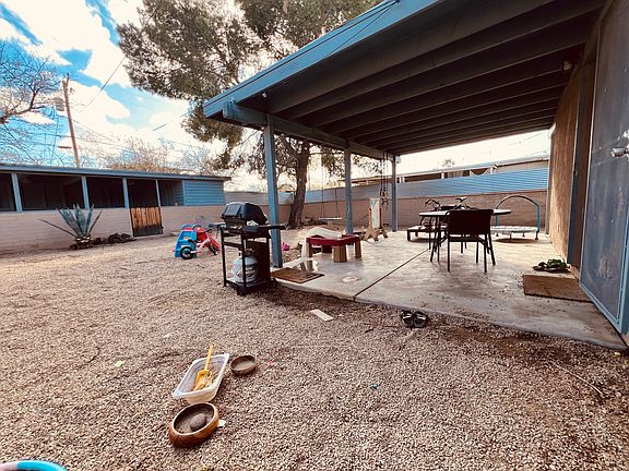 large covered patio in the private back yard. View of the carport and small storage area.