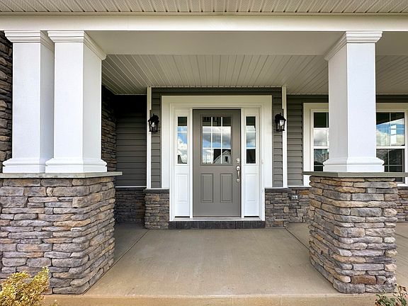 Front porch with white columns on both sides, accent stone halfway up - facing the front door.