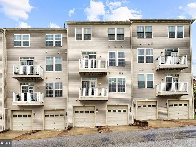 Exterior rear with attached garage and additional driveway parking space.