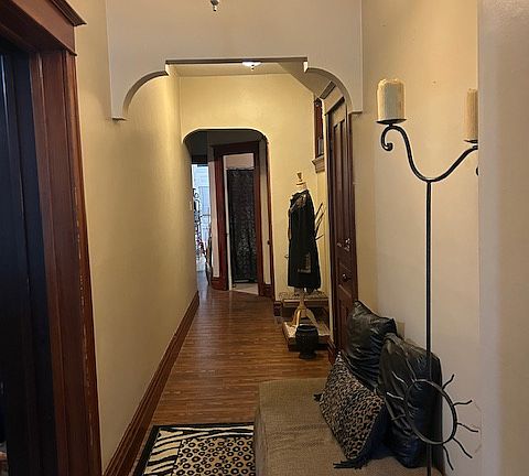 Arched hallway with pocket door leading to kitchen, bathroom, and bedroom.