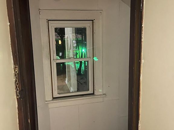 View of the back yard through the window. The stairs leading to the exit are on the right and the bathroom on the left to each side of that window.