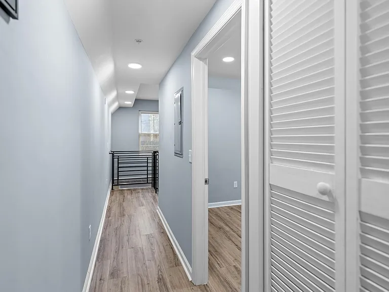 Hallway with bedroom door to the right and stairs to the lower level beyond.