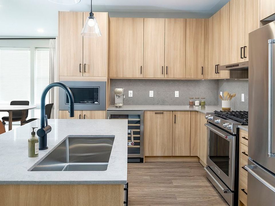 Signature Collection kitchen with stainless steel appliances (wine fridge included), quartz countertops, quartz tile backsplash, oak cabinetry, and hard-surface flooring