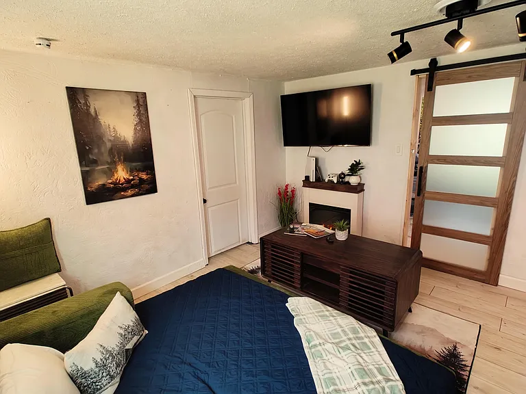 Furnished bedroom featuring a full bed, wall-mounted TV, and a stylish barn door for added privacy and easy access.