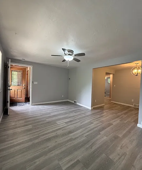 Living room with main entry door on the left, dining area and throughway to rest of unit on the right.