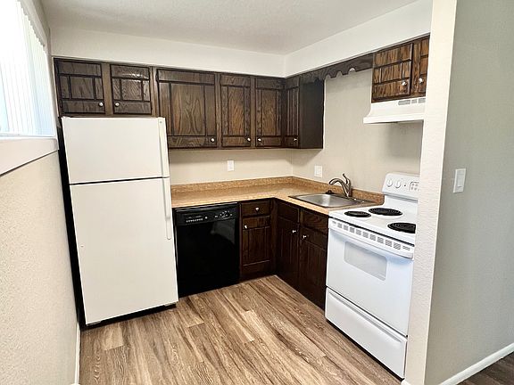 Charming kitchen with sleek wooden cabinets, modern appliances, and elegant wood flooring for a cozy culinary experience.