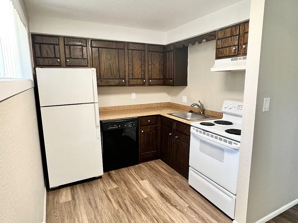 Charming kitchen with sleek wooden cabinets, modern appliances, and elegant wood flooring for a cozy culinary experience.