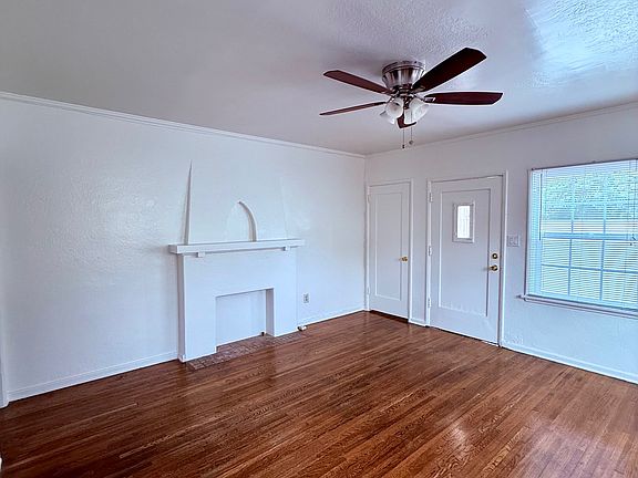 Large living room with charming faux fireplace and ceiling fan