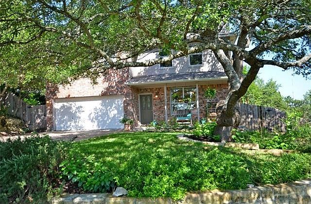 Natural and drought resistant landscaping beds frame this beautiful yard with majestic oak.