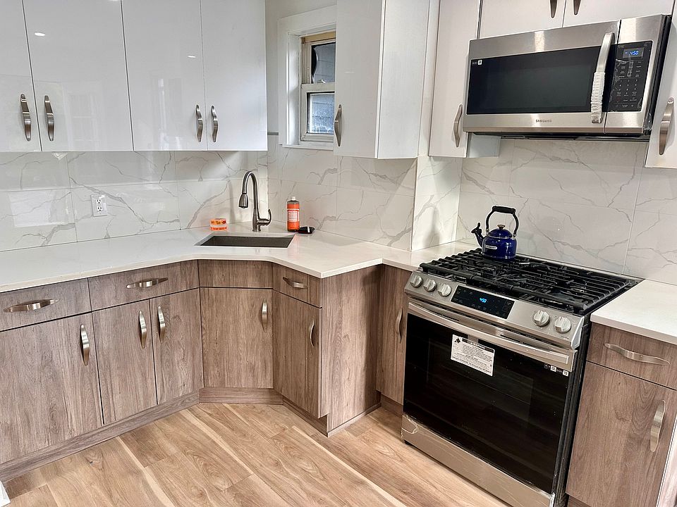 Newly renovated kitchen with modern appliances and corner stainless steel sink.