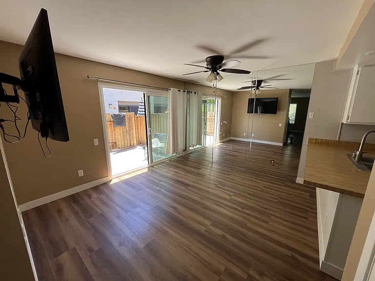 Dining room with full wall mirror, ceiling fan, TV mount and patio entry.