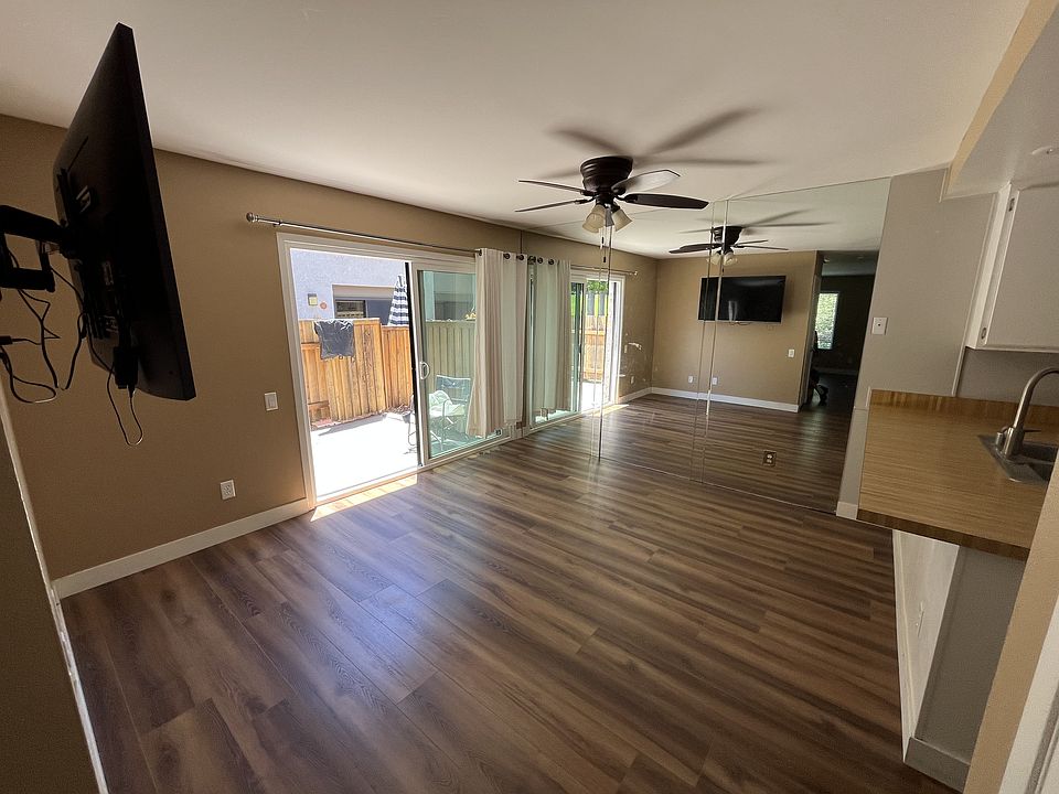 Dining room with full wall mirror, ceiling fan, TV mount and patio entry.