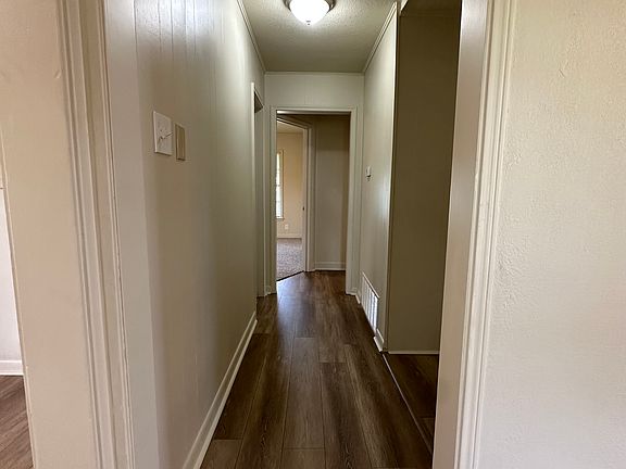 hallway off living area, kitchen opening on left, washer/dryer opening on right of hall, bathroom on left, bedroom 2 at end of hall, bedroom 3 to right
