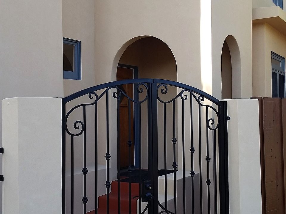Front elevation of gated entry to front door and Juliet balcony above front entry