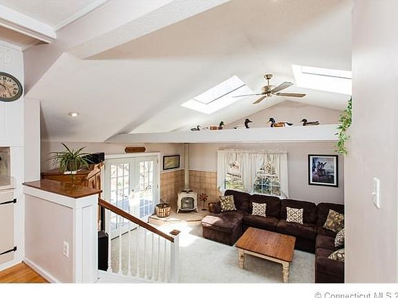 View of Living room from the Dining room. Skylights and vaulted ceilings with beams create a bright and open, comfortable gathering space.