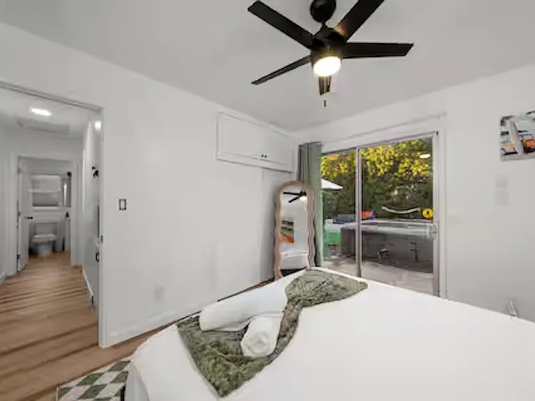 Bedroom 1 features a queen bed with access to the outdoor area, providing a light-filled, comfortable space to rest and recharge. Ceiling fan and ample storage complete this convenient room.
